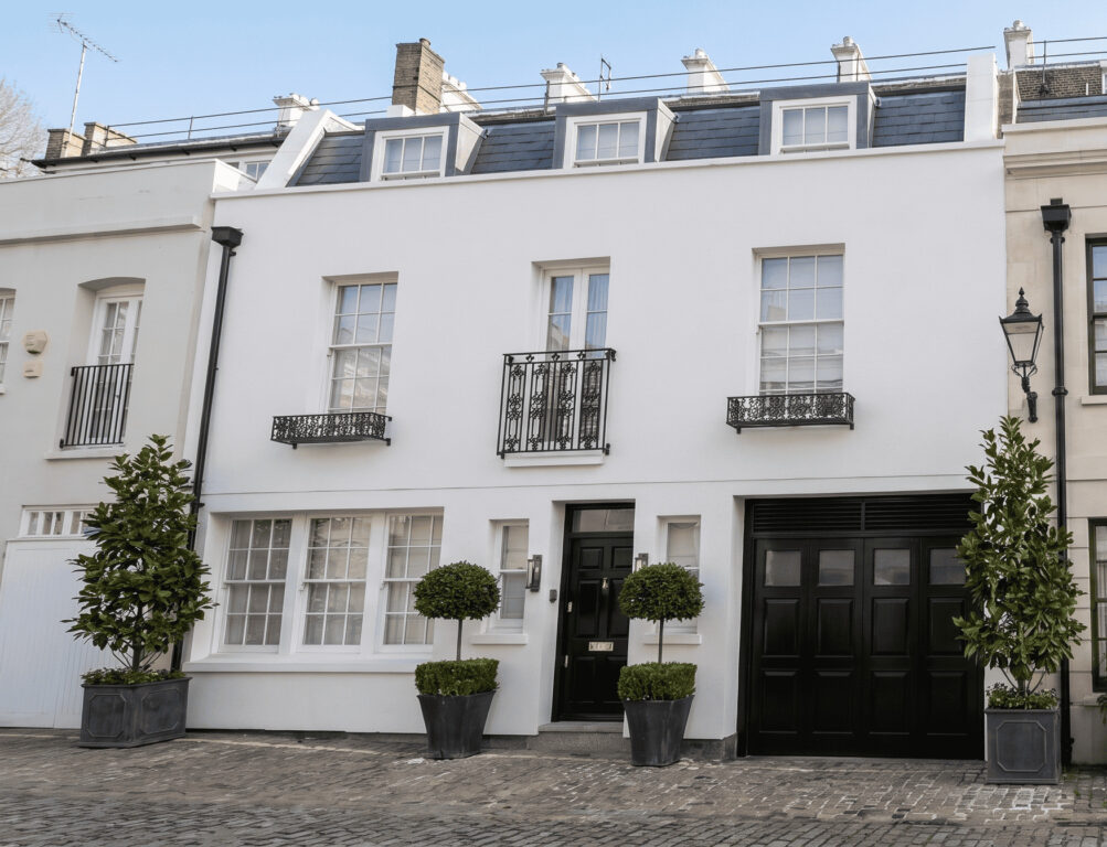 White stucco London mews houses with clipped topiary and garage doors