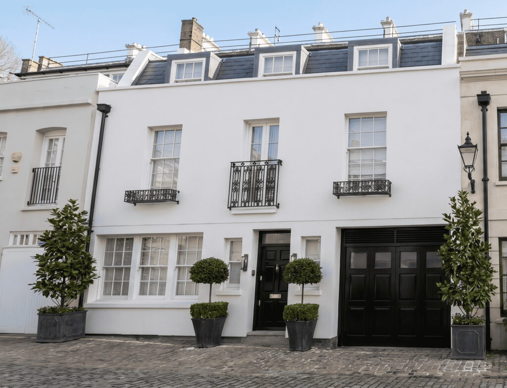 White stucco London mews houses with clipped topiary and garage doors